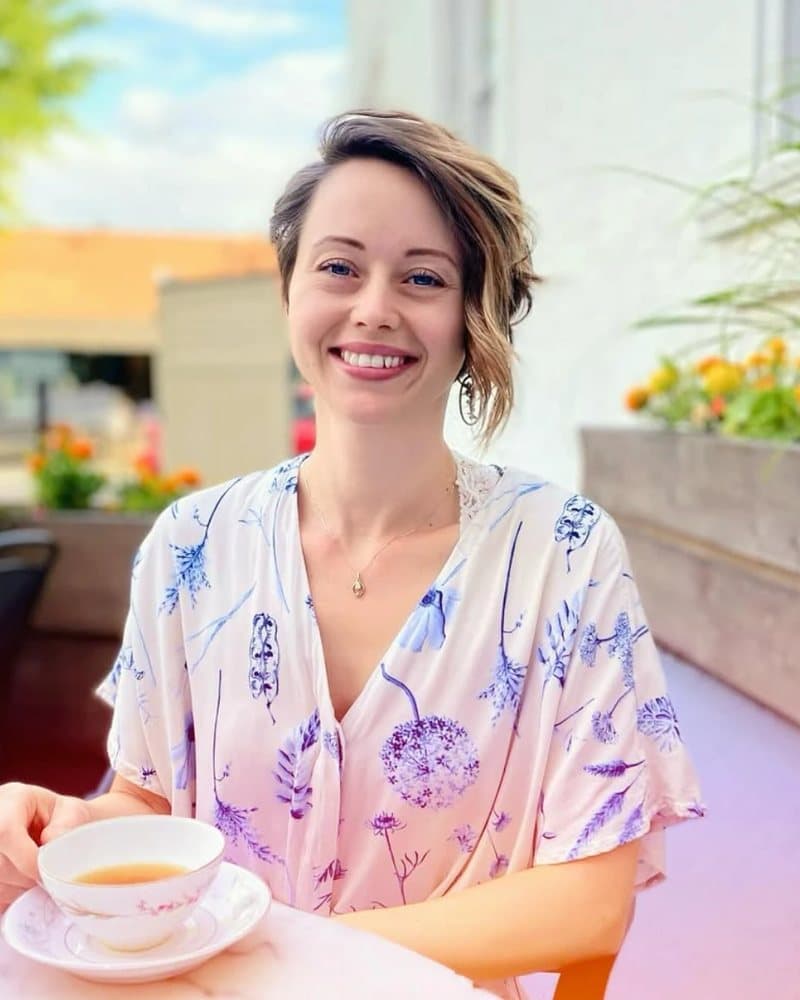 Mary Marie smiling at an outdoor cafe table with a cup of tea